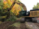 Clearing brush and trees next to road with backhoe