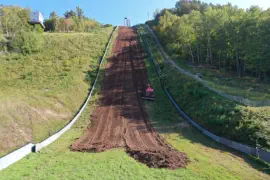 Machine smoothing out ski jump hillside